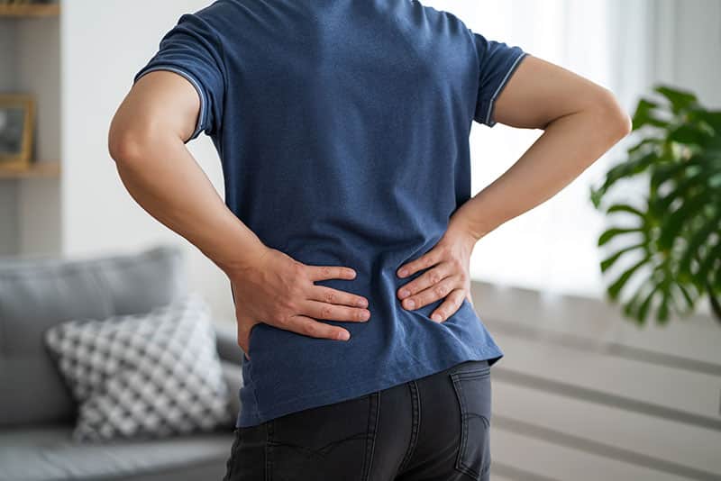 Back pain, kidney inflammation, man suffering from backache at home